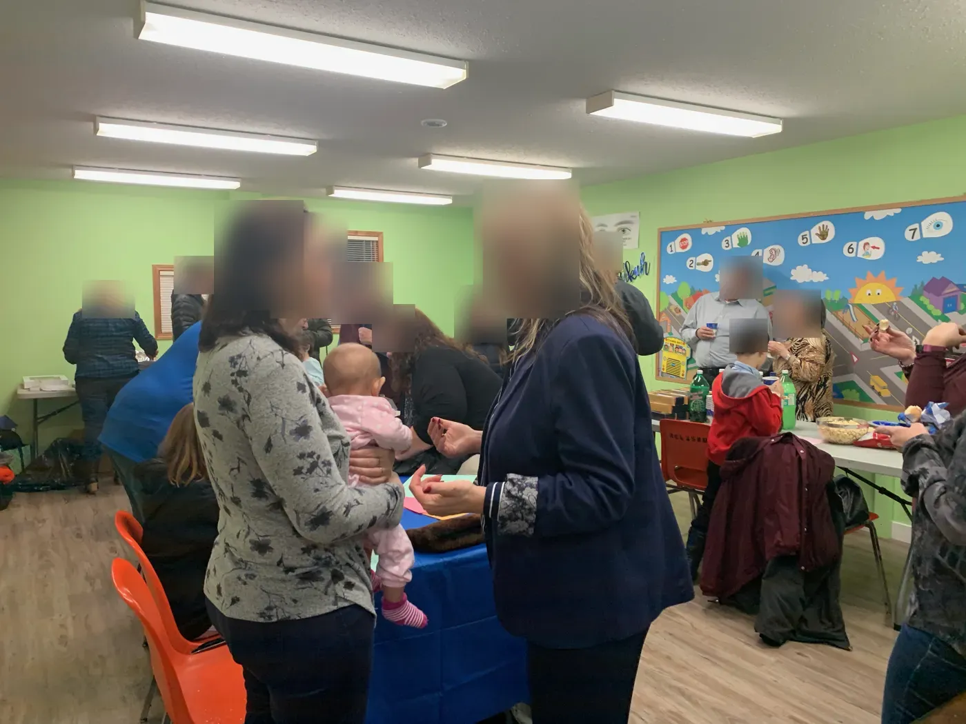 Parents, grandparents and children talking and sharing snacks in a brightly painted community room at the Torah2Go Chanukah event, Red Deer, 2019